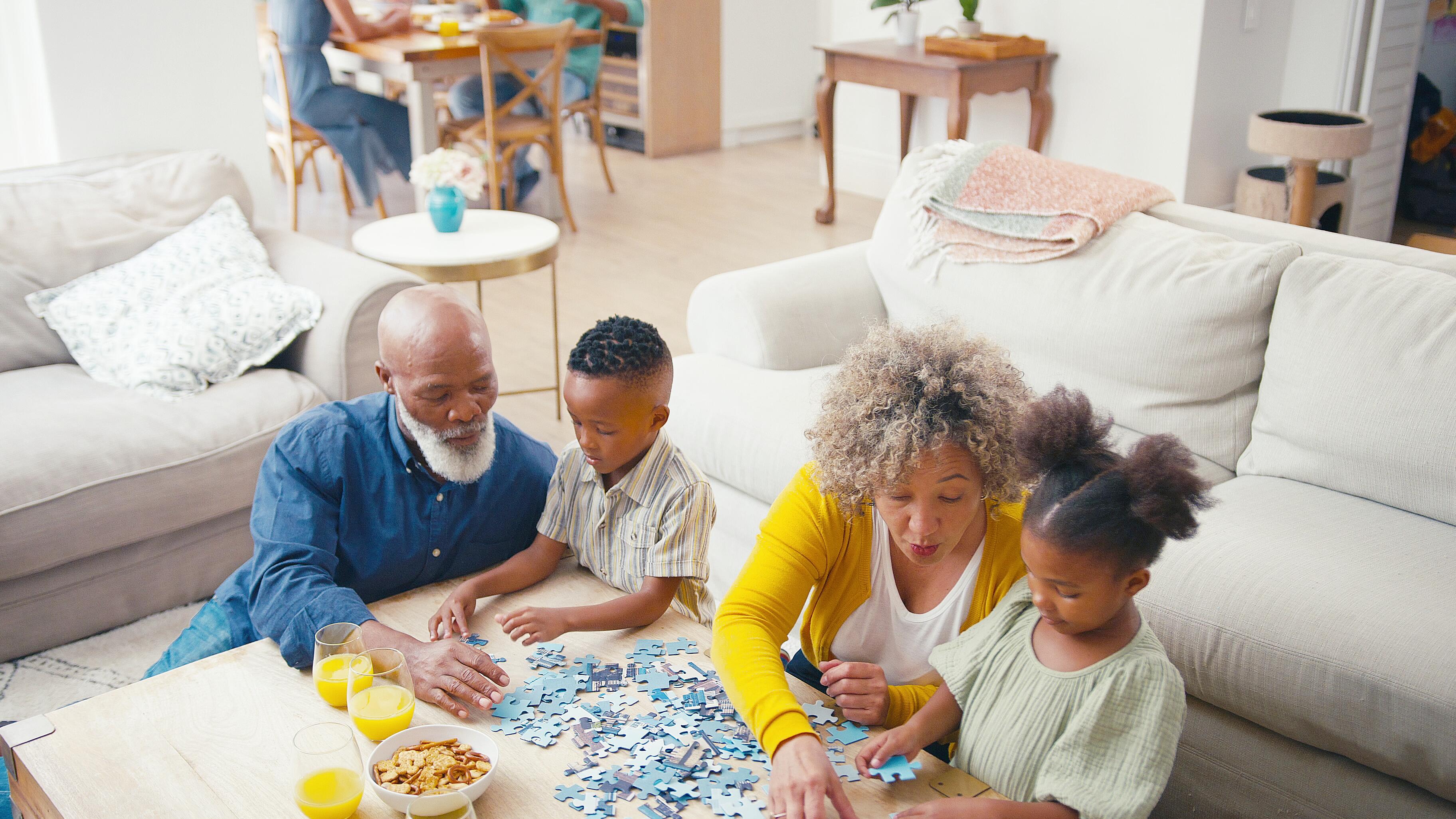 Two siblings cooperating to finish a jigsaw puzzle indoors