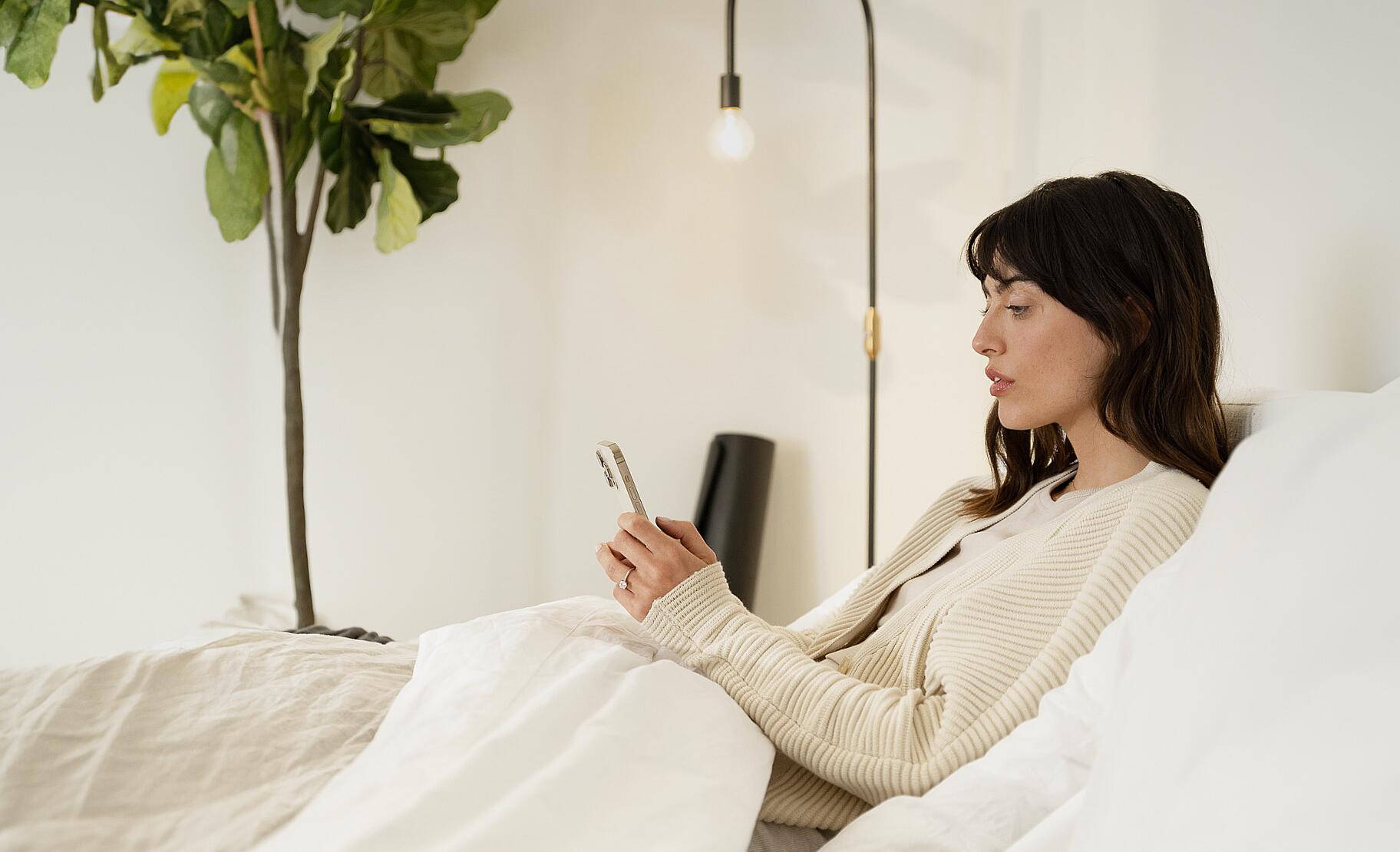 Person placing smartphone away 30 minutes before sleep to reduce blue light