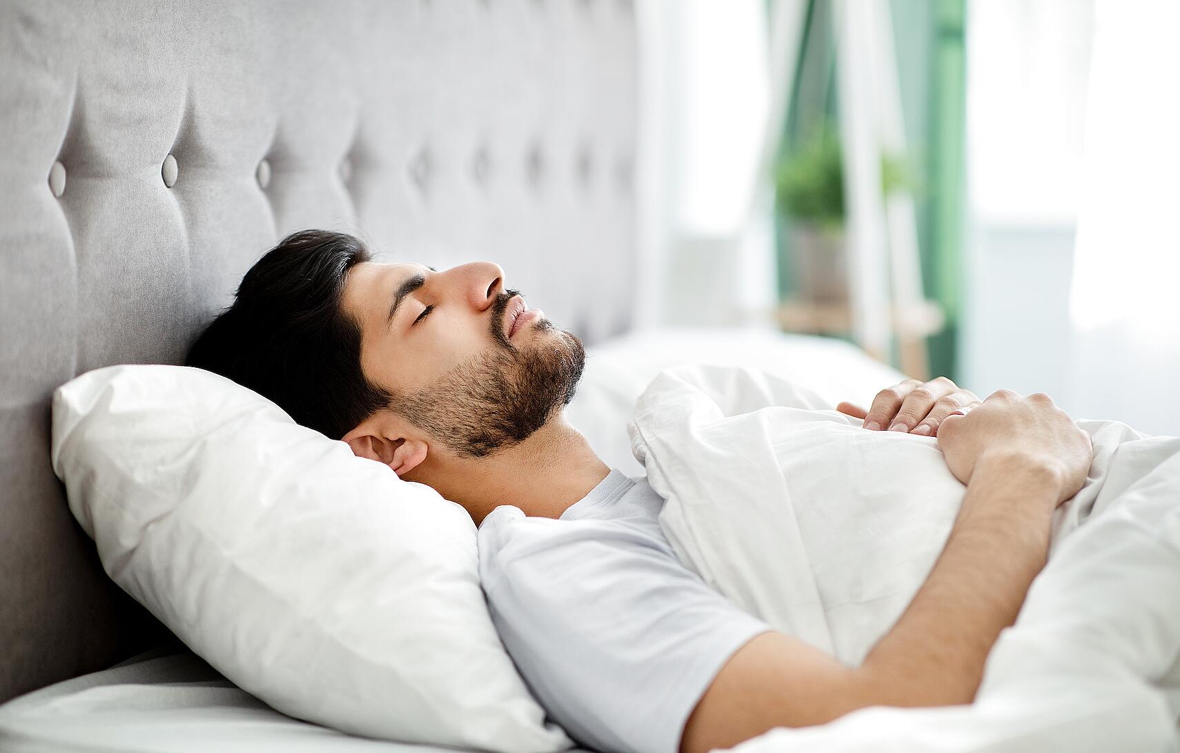Individual performing guided body scan meditation lying down at home