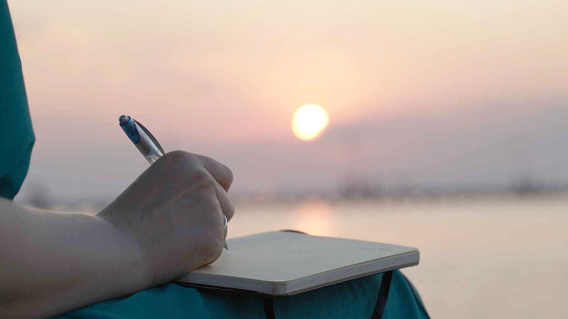 Close-up of person writing in gratitude journal during calm morning