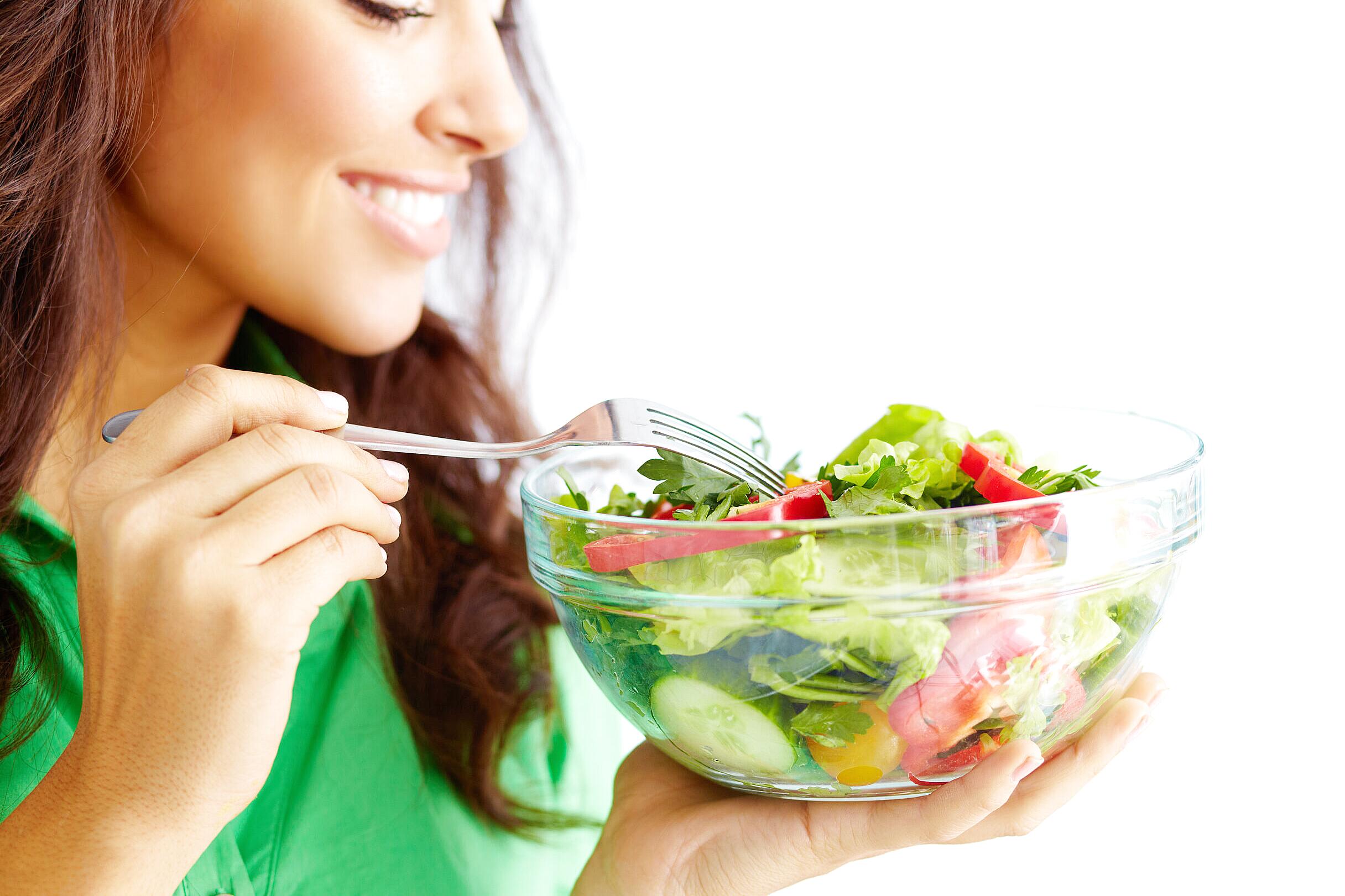 Individual practicing mindful eating by focusing on salad textures and taste